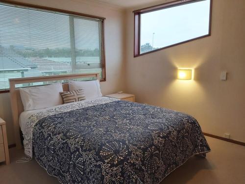ein Schlafzimmer mit einem Bett und einem großen Fenster in der Unterkunft Beachside Townhouse Dunedin in Dunedin