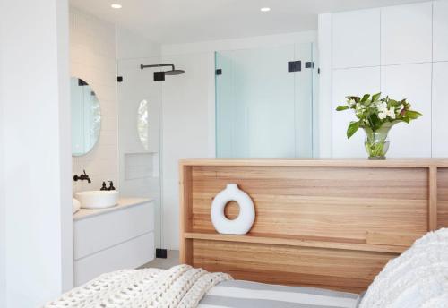 ein Schlafzimmer mit Dusche und Waschbecken mit einer Blumenvase in der Unterkunft Coomalie in Palm Beach