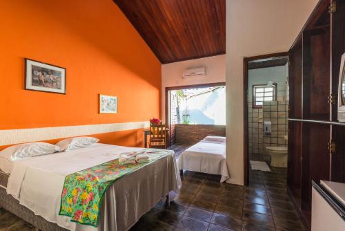1 dormitorio con paredes de color naranja, 1 cama y baño en Vale Verde Coroa Vermelha, en Santa Cruz Cabrália