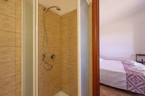 une douche dans une salle de bain avec un lit dans l'établissement Casa Ginestre piscina e vista mare, à Aglientu