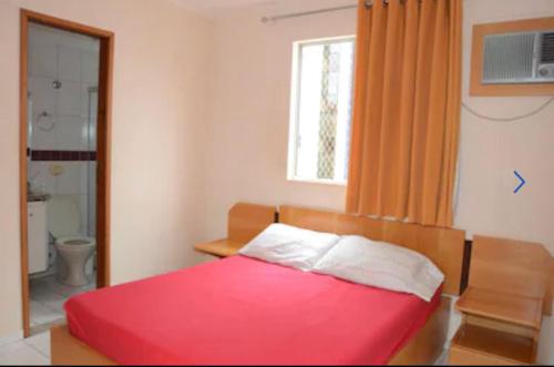 a bedroom with a red bed and a window at Apartamento 3 quarto com ótima área de lazer in Caldas Novas