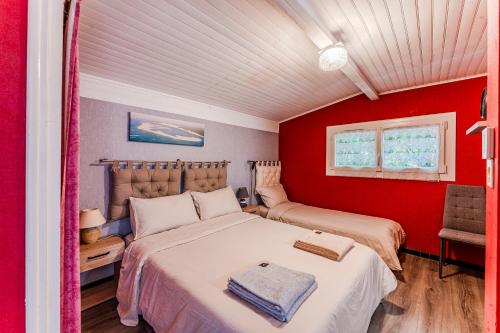 a bedroom with two beds and a red wall at Villa Eva in Biscarrosse-Plage