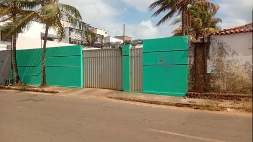 a green fence on the side of a street at Casa para temporada pertinho do mar in São-José-do-Ribamar