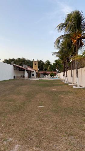 a yard with palm trees in front of a building at Casa para temporada pertinho do mar in São José de Ribamar
