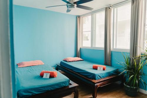 two beds in a room with blue walls and windows at Polynesian Hostel Beach Club in Honolulu