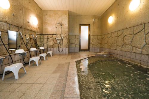 a bathroom with a pool of water with toilets and sinks at ホテルララプラス in Nirasaki