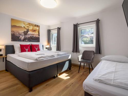 a bedroom with two beds and a chair at Chalet Hornblick in Fieberbrunn