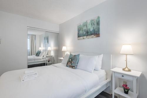 a white bedroom with a large white bed and a mirror at Spacious and Cozy 1BR - Near Old Port in Montréal