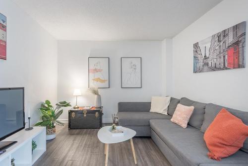 a living room with a gray couch and a tv at Spacious and Cozy 1BR - Near Old Port in Montréal