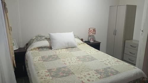 a bedroom with a bed with a quilt on it at Casa centro de Villarrica in Villarrica
