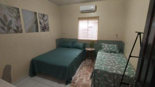 ein kleines Schlafzimmer mit zwei Betten und einem Fenster in der Unterkunft Casa Marupiá - Natureza, simplicidade e bem-estar a poucos minutos do centro de Belém in Ananindeua