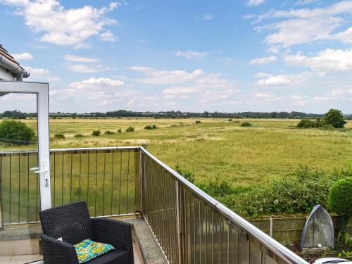 einen Balkon mit einem Stuhl und Blick auf ein Feld in der Unterkunft The Boat House in Canterbury
