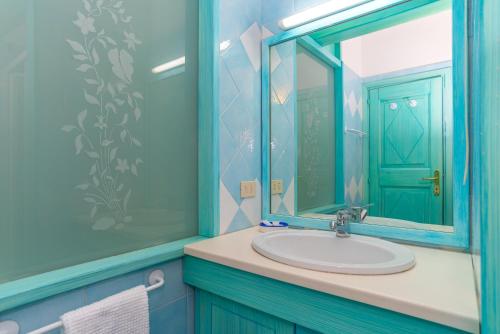 a blue bathroom with a sink and a mirror at Conchiglia Blu in Barrabisa