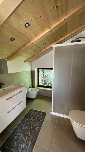 Un baño con dos lavabos y un inodoro y una ventana. en Truma Swing Castelfondo, en Castelfondo