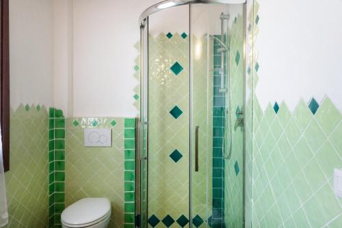 a bathroom with a shower with a toilet and green tiles at Casa vacanza Stazzu Saiacciu in Palau