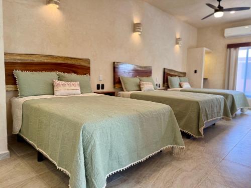 a bedroom with two beds with green comforters at CASA VICTORIA in Chichén-Itzá