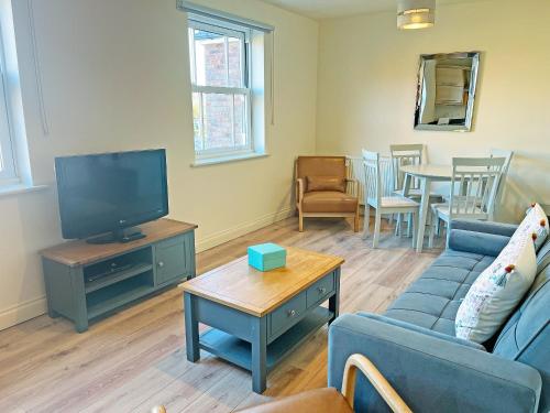 a living room with a couch and a tv and a table at Solara Breeze in Reighton