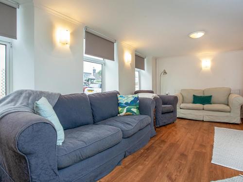 a living room with a blue couch and two chairs at Barnhay Cottage in Totnes