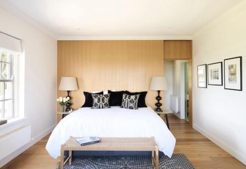 a bedroom with a large white bed and a bench at Hazelwood House in Mittagong