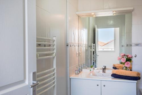 レ・サ​​ーブル・ドロンヌにあるAppart Villa Margaux proche merの洗面台と鏡のある白いバスルーム