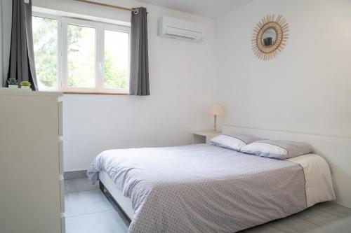 a white bedroom with a bed and a window at Individual Guest House - Between Paris and Disneyland in Vaires-sur-Marne