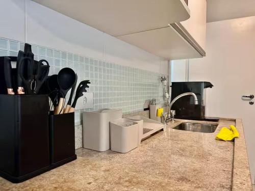 eine Küche mit einer Spüle und einer Theke mit Küchenutensilien in der Unterkunft Apartamento para aluguel de temporada in Bertioga