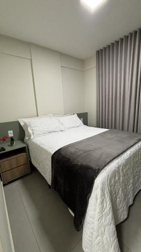 Un dormitorio con una cama grande y una mesita de noche. en Studio Live 2 Moderno e Aconchegante, en Uberlândia