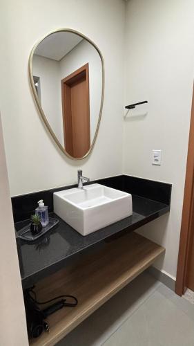 Un baño con un lavabo blanco y un espejo. en Studio Live 2 Moderno e Aconchegante, en Uberlândia