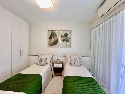 2 Betten in einem weißen Zimmer mit grüner Bettwäsche in der Unterkunft Apartamento para aluguel de temporada in Bertioga