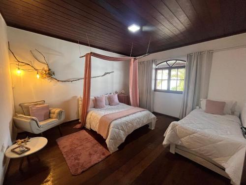 アハイアウ・ド・カボにあるFlor de Alissah Pousada & Bistroのベッド2台と椅子と窓のある寝室