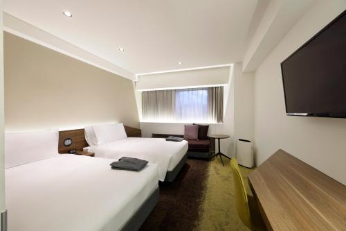 a hotel room with two beds and a flat screen tv at Holiday Inn & Suites Sapporo Odori Park by IHG in Sapporo