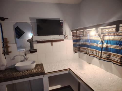 ウユニにあるCABAÑAS SAL y PIEDRAの洗面台と壁掛けテレビ付きのバスルーム