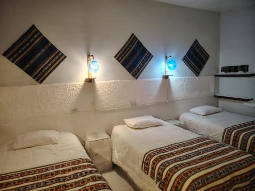 ウユニにあるCABAÑAS SAL y PIEDRAのベッド2台 壁に照明が付く部屋