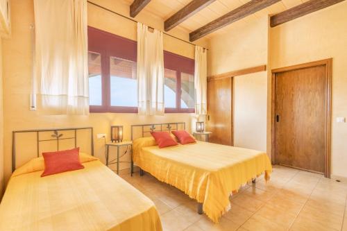 two beds in a room with two windows at Cal Maso in Hostafranco