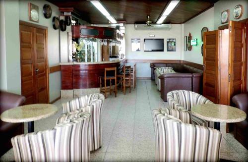 a restaurant with chairs and tables and a bar at Hotel Radar in Gravataí