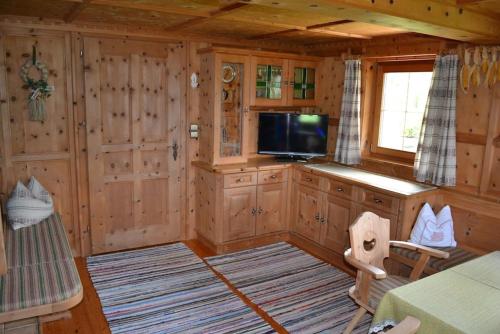 a living room with wooden walls and a television in a cabin at Ferienhaus Obersäuling in Stummerberg