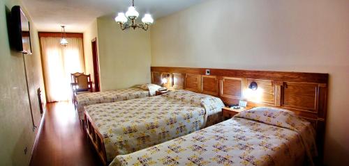 a hotel room with two beds and a chandelier at Hotel Sagres in Campos do Jordão