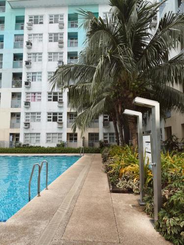 a swimming pool with palm trees and a building at 90's Themed 2 Bedroom Unit at Seawind Sasa, Davao City Philippines in Sampong