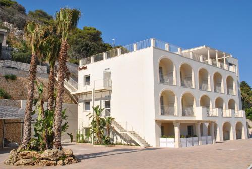 a white building with palm trees in front of it at Est hotel in Santa Cesarea Terme