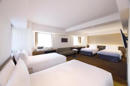 a hotel room with two beds and a couch at Holiday Inn & Suites Sapporo Odori Park by IHG in Sapporo