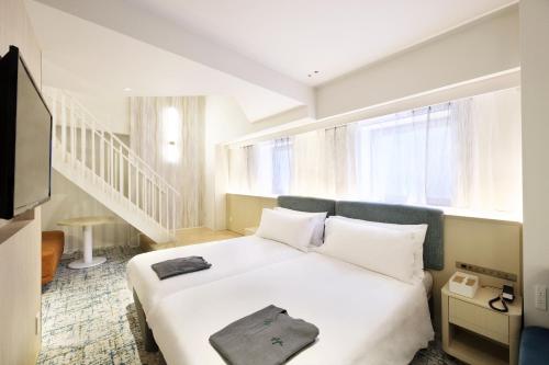 a bedroom with a large white bed and a staircase at Holiday Inn & Suites Sapporo Odori Park by IHG in Sapporo