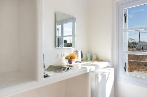 a white bathroom with a mirror and a sink at Aegean Blue Santorini Perivolos 1 in Perivolos