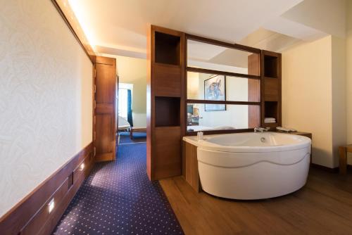 a large bathroom with a tub and a mirror at Hostellerie de la Pointe Saint-Mathieu - SPA & Restaurant in Plougonvelin