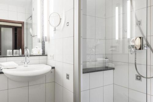 uma casa de banho branca com um lavatório e um chuveiro em Trip Inn Stadthotel Coburg em Coburgo
