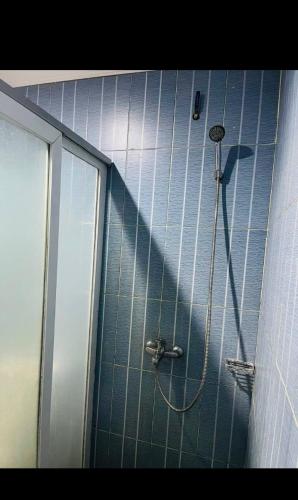 a shower with a hose in a blue tiled bathroom at RatanakCity hotel in Banlung