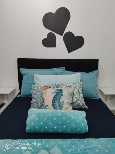 a bed with blue pillows and black hearts on the wall at Hospedagem MAR SANTO in Florianópolis