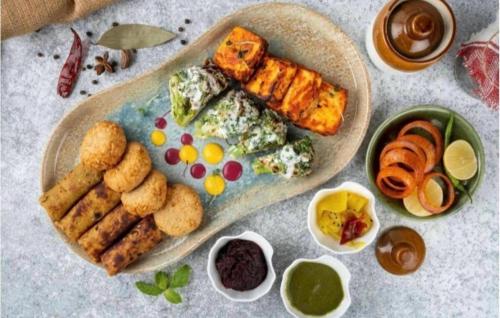 a plate of food with food on a table at Hotel Rosewood-Near Delhi Airport-Free Airport Drop in New Delhi