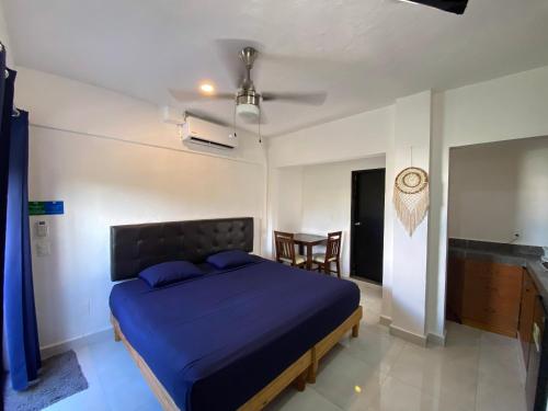 a bedroom with a blue bed and a table at Maui Hostels Playa del Carmen in Playa del Carmen