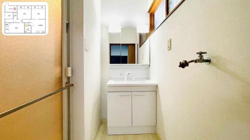 a small bathroom with a sink and a mirror at eyehouse ozu No1 in Ozu