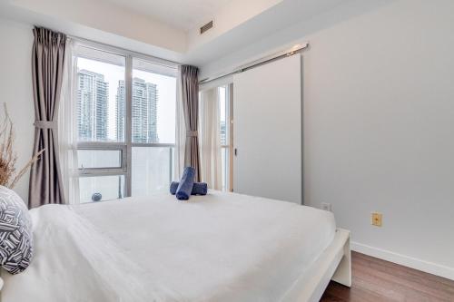 a bedroom with a large white bed with a window at Modern 2 BR Condo - By Scotiabank Arena - City View in Toronto